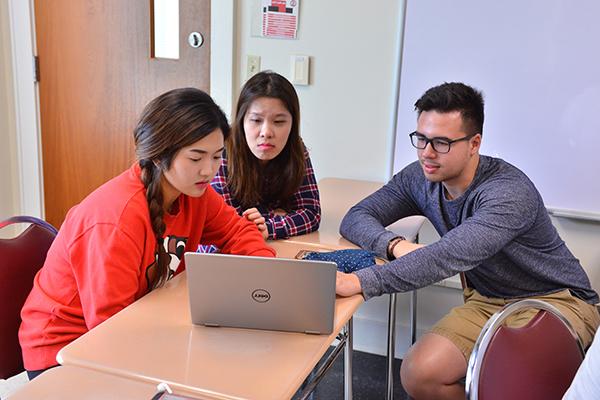 三个学生围在一台电脑周围